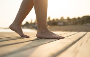 Detail of female barefoot feet on sunny beach